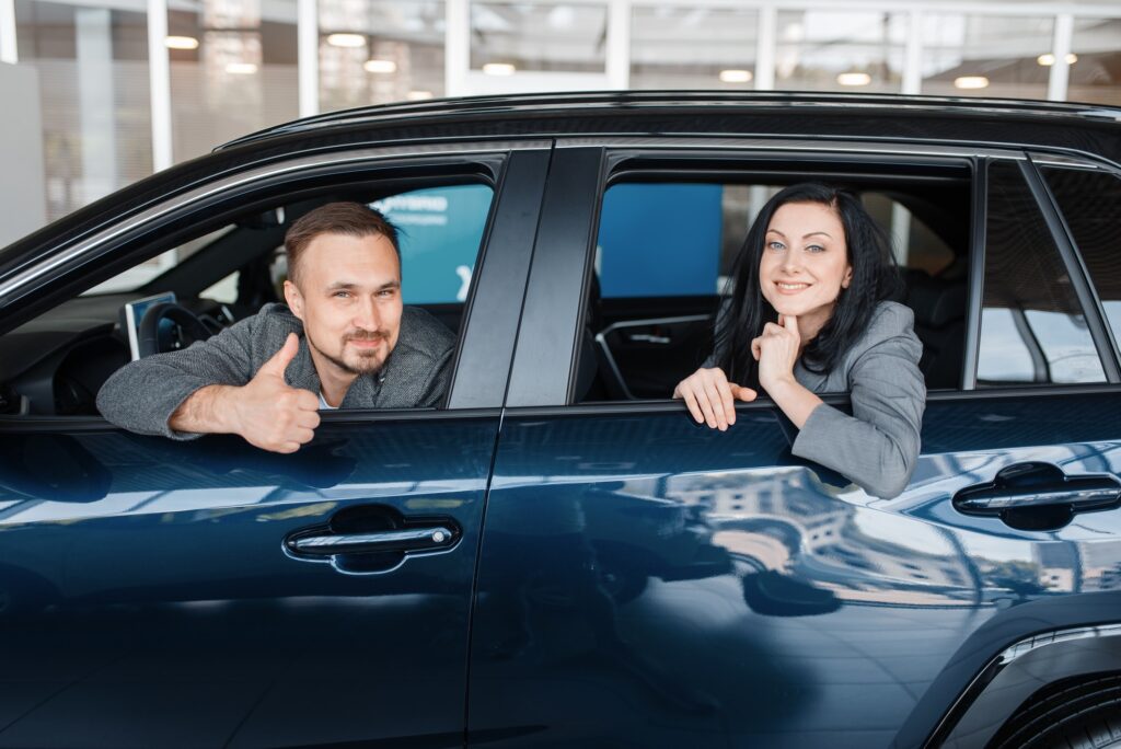 happy couple sitting in new car showroom.jpg